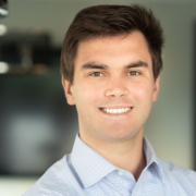 A man with brown hair and blue shirt smiling.