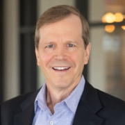 A man in a suit and tie smiling for the camera.