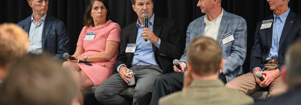 A group of people sitting on chairs in front of a microphone.