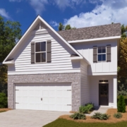 A white house with a garage and trees in the background.