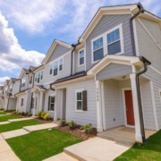 A row of houses with grass and sky in the background.