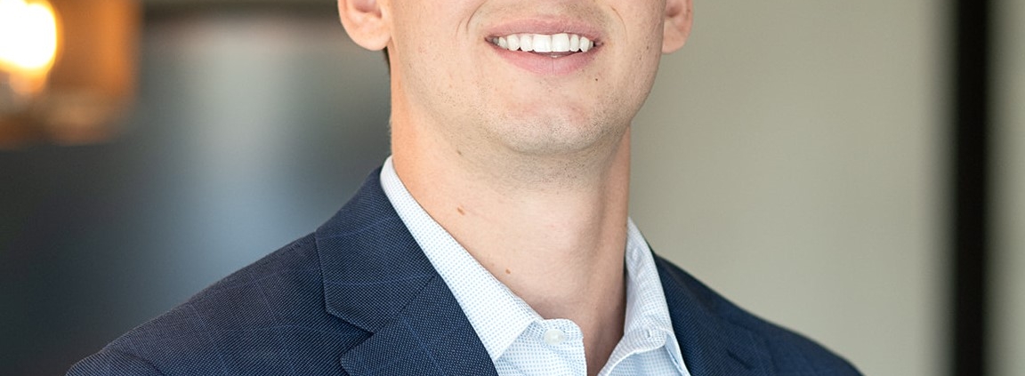 A man in a suit and tie smiling for the camera.
